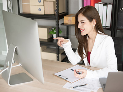 Happy business woman pointing at computer screen after finding a business telephone service provider